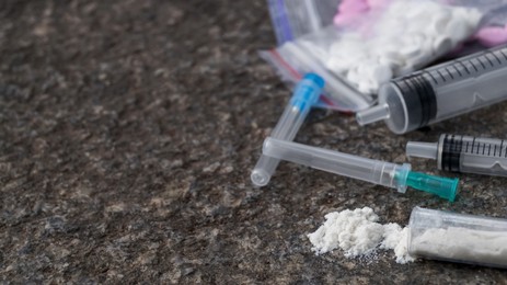 Photo of Pills, syringes and powder on stone surface, closeup with space for text. Hard drugs