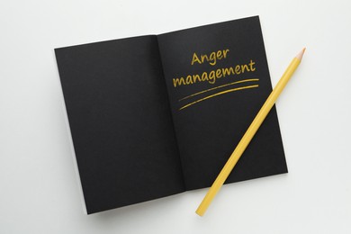 Photo of Notebook with text Anger Management and yellow pencil on white background, top view