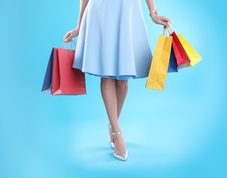 Young woman with shopping bags on color background, closeup of legs