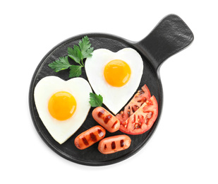 Slate plate of tasty breakfast with heart shaped fried eggs and sausages isolated on white, top view