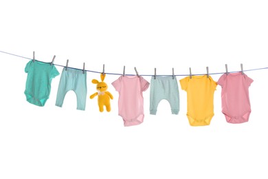 Colorful baby clothes and toy drying on laundry line against white background