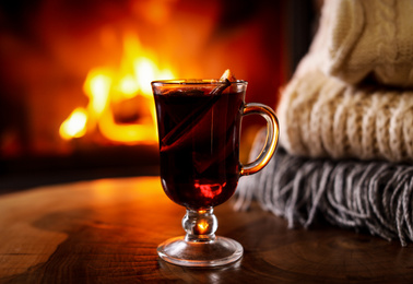 Tasty mulled wine, knitwear and blurred fireplace on background