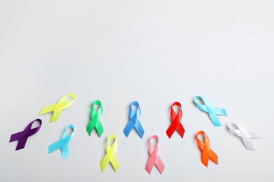 Different colorful ribbons on white background, flat lay with space for text. World Cancer Day