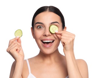 Beautiful young woman putting slices of cucumber on eyes against white background