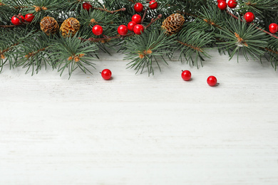 Composition with fir branches and berries on white wooden background, space for text. Winter holidays