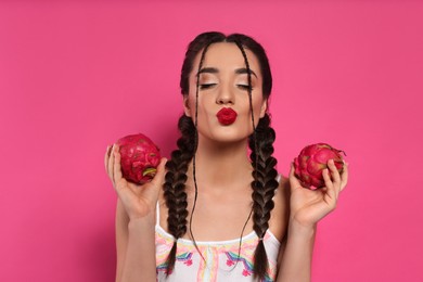 Photo of Young woman with fresh pitahayas on pink background. Exotic fruit