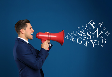 Handsome man with megaphone and letters on blue background. Speech therapy concept