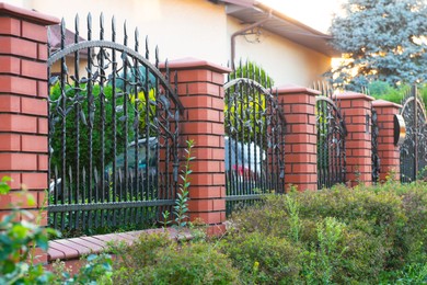 Bushes and beautiful brick fence with iron railing outdoors