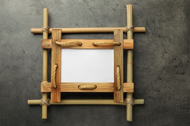 Empty bamboo frame on grey table, top view