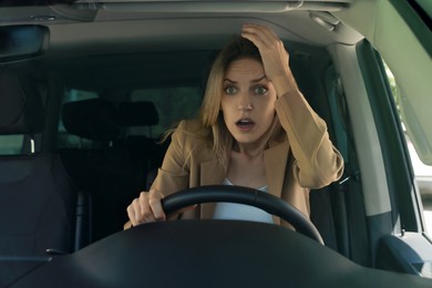 Photo of Stressed angry woman in driver's seat of modern car, view through windshield