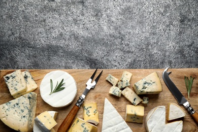 Cheese platter with specialized knife and fork on grey table, flat lay. Space for text