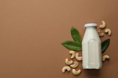 Vegan milk and cashew nuts on brown background, flat lay. Space for text