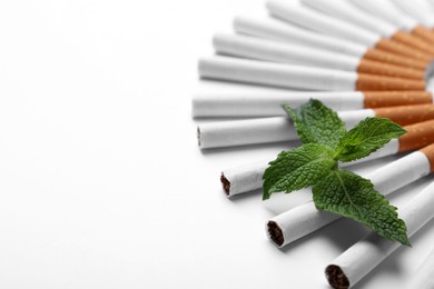 Menthol cigarettes and fresh mint leaves on white background. Space for text