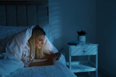 Photo of Young woman using tablet in bed at night. Sleeping disorder problem