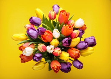 Photo of Bouquet of beautiful colorful tulips on yellow background, top view