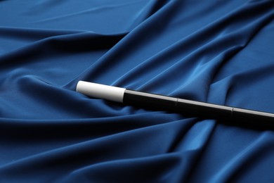 Beautiful black magic wand on blue fabric