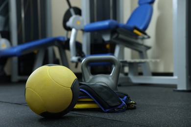 Yellow medicine ball, kettlebell and weighting agents on floor in gym, space for text