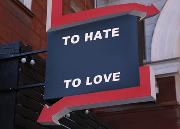 Sign with different directions - TO HATE or TO LOVE on building outdoors
