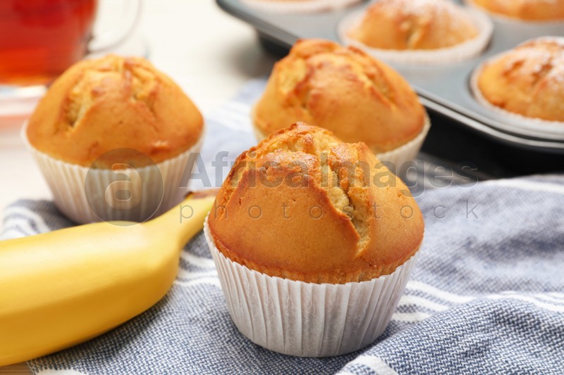 Photo of Tasty muffins and ripe banana on table, closeup