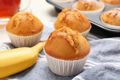 Tasty muffins and ripe banana on table, closeup
