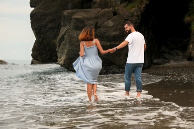 Young couple walking on beach near sea