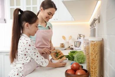 Mother and daughter peeling vegetables at kitchen counter