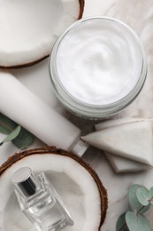 Different hand care cosmetic products, coconut pieces and eucalyptus branch on table, flat lay