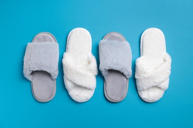 Different soft fluffy slippers on light blue background, flat lay
