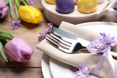 Festive Easter table setting with floral decor on wooden background, closeup