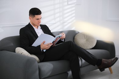 Man reading new magazine on sofa indoors