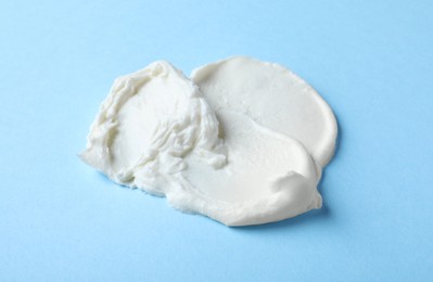 Smear of delicious cream cheese on light blue background