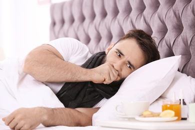 Ill man suffering from cough in bed at home