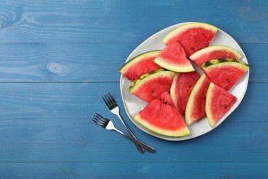 Plate with slices of juicy watermelon on blue wooden table, top view. Space for text