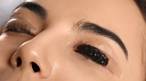 Young woman undergoing eyelash lamination and tinting, closeup