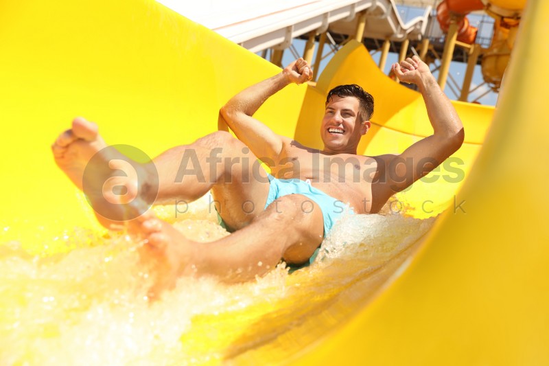 Man on slide at water park. Summer vacation