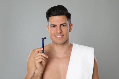 Handsome man with razor after shaving on grey background