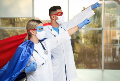 Doctors wearing face masks and capes indoors. Super hero power for medicine