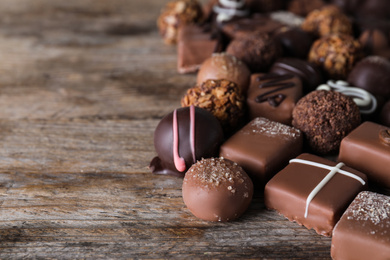 Photo of Different delicious chocolate candies on wooden table