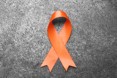 Orange ribbon on grey table, top view. Multiple sclerosis awareness