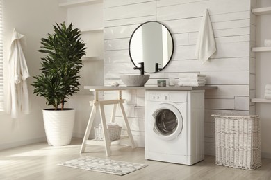 Stylish bathroom interior with modern washing machine