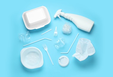 Different plastic items on light blue background, flat lay