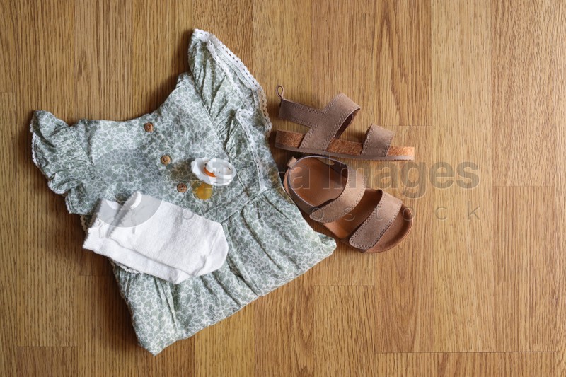 Stylish child clothes, shoes and accessories on wooden background, flat lay