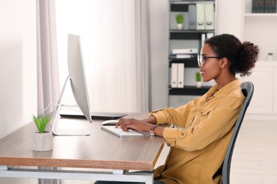 Photo of African American intern working with computer at table in office