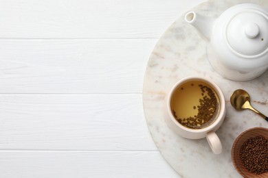 Photo of Freshly made buckwheat tea served on white wooden table, top view. Space for text