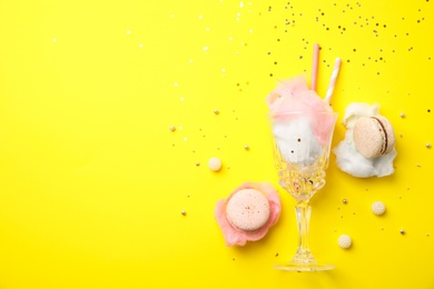 Flat lay composition with sweet cotton candy on yellow background, space for text