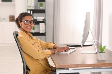 Photo of Smiling African American intern working with computer at table in office