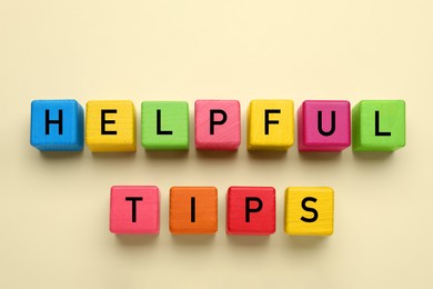 Phrase Helpful Tips made of colorful cubes with letters on beige background, top view