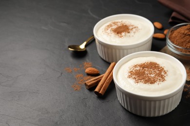 Delicious semolina pudding with cinnamon on black table, space for text