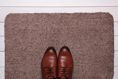 New clean door mat with shoes on white wooden floor, top view