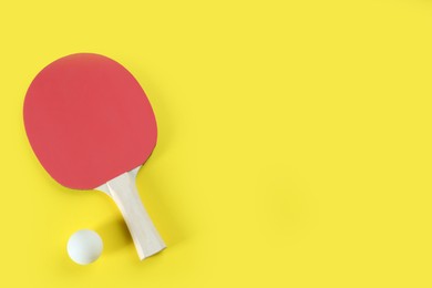Ping pong racket and ball on yellow background, flat lay. Space for text